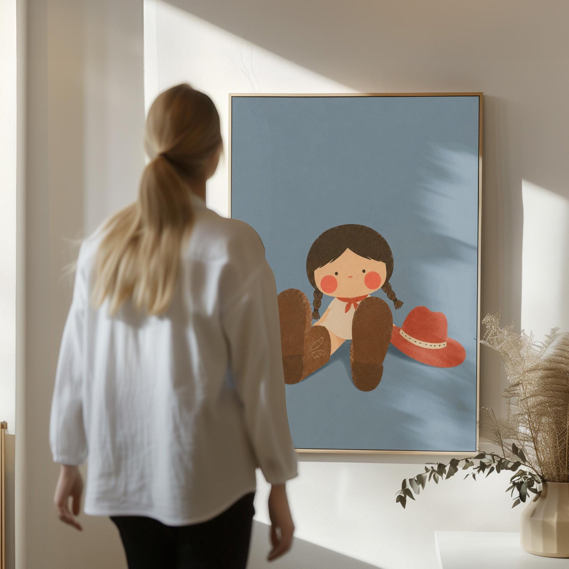 Little cowgirl sitting with big brown boots and a red hat, canvas wall art hanging in a calm, modern living space
