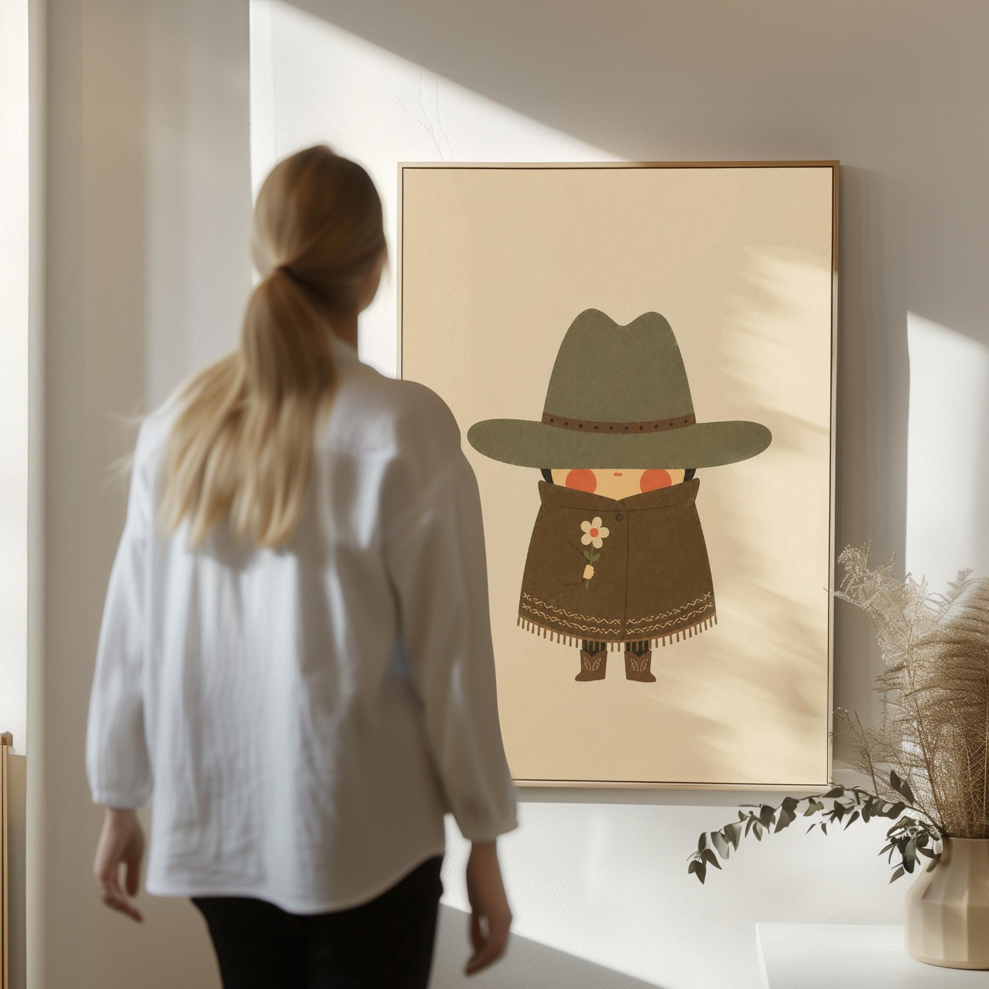 Tiny cowboy in a wide hat and fringed coat holding a daisy, canvas wall art presented in a light, minimal room