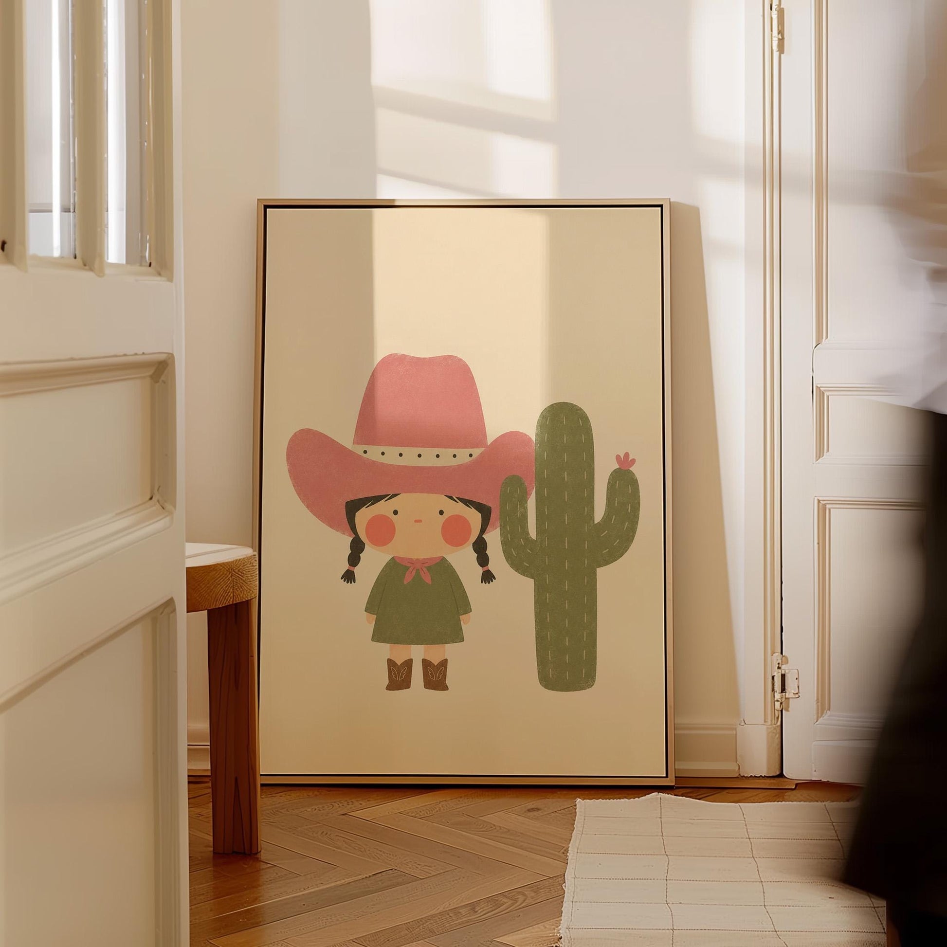 Little cowgirl in a pink hat next to a tall flowering cactus, canvas print seen in a warm interior with natural light