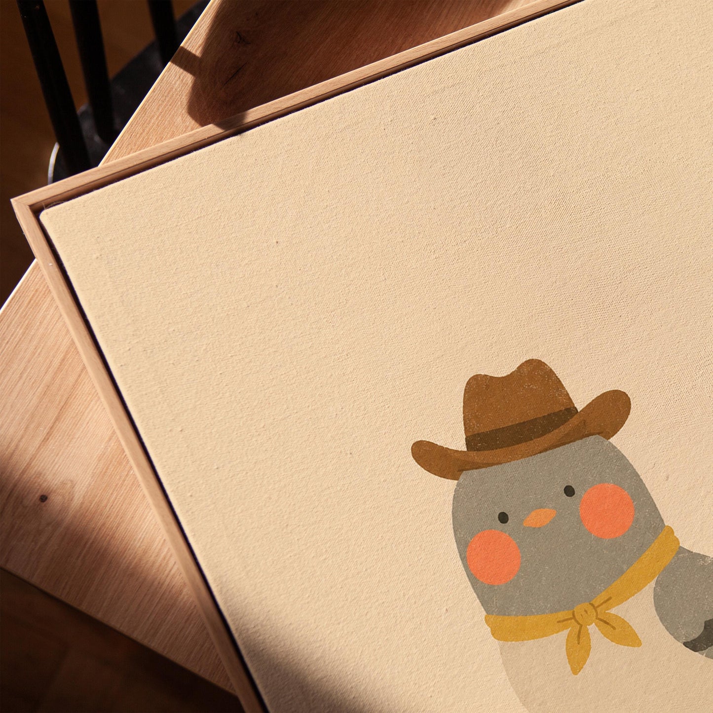 Round grey bird wearing a tiny cowboy hat and yellow bandana, canvas print in a warm, minimally styled interior