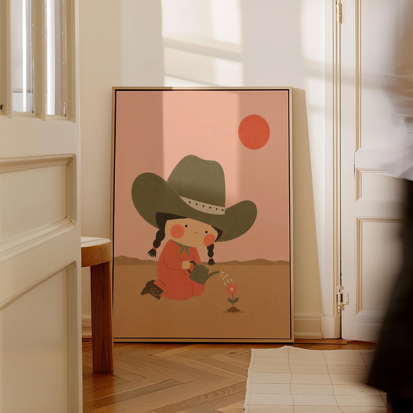 Cowgirl in a green hat watering a small flower in the desert, canvas print styled against a soft white wall