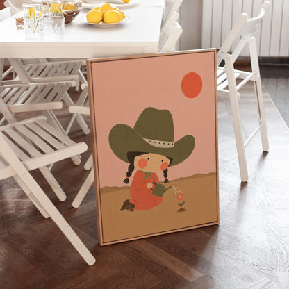 Cowgirl in a green hat watering a small flower in the desert, canvas print presented in a light, minimal room
