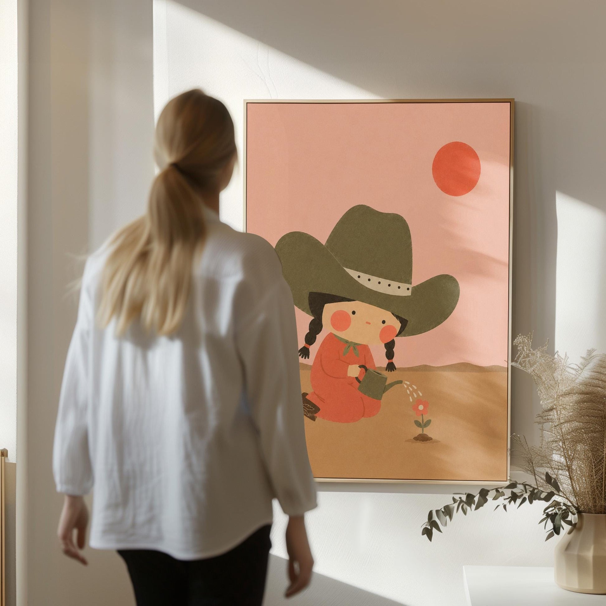 Cowgirl in a green hat watering a small flower in the desert, canvas print on a quiet wall in a considered interior