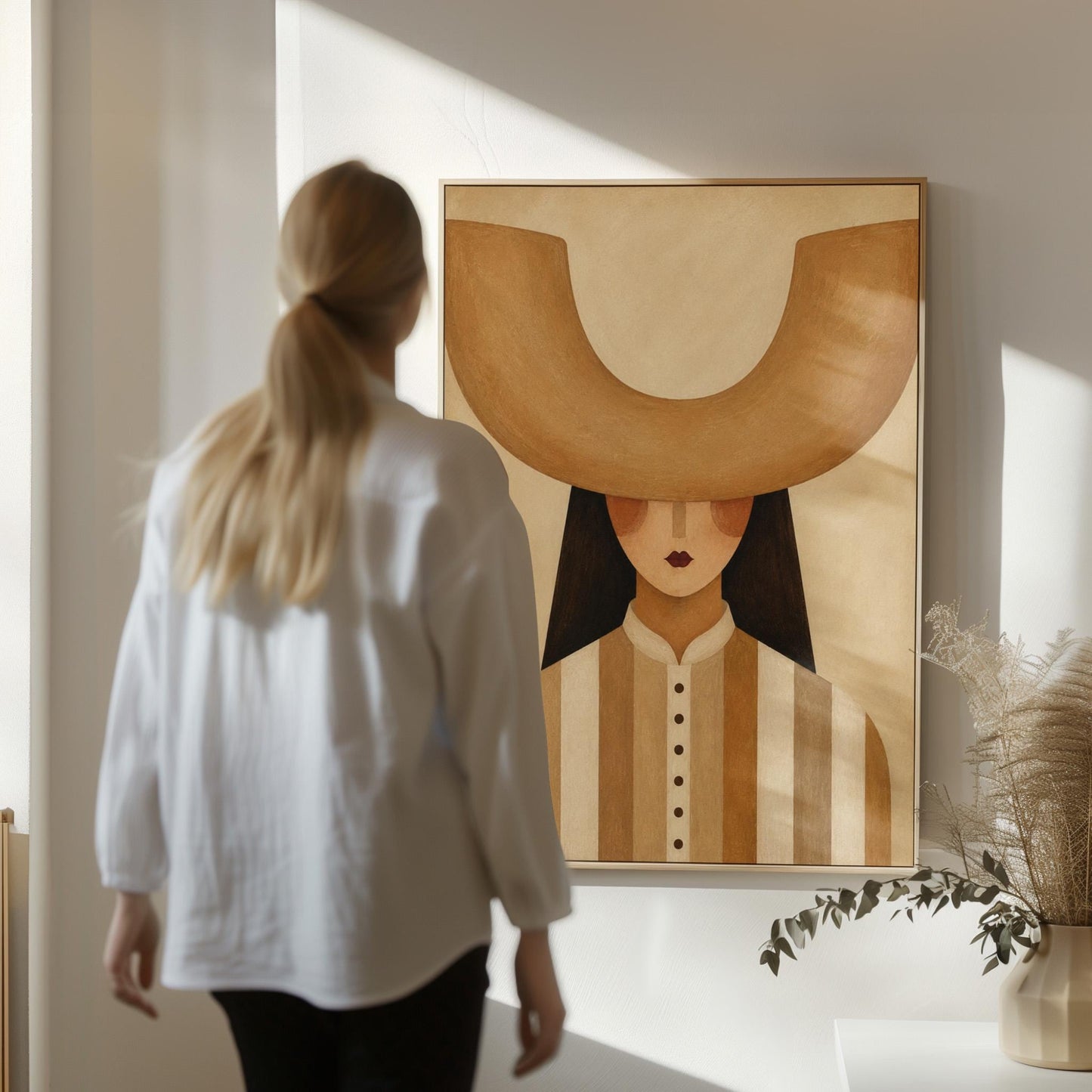 Faceless cowgirl under an enormous curved tan cowboy hat brim shape, canvas print seen in a warm interior with natural light