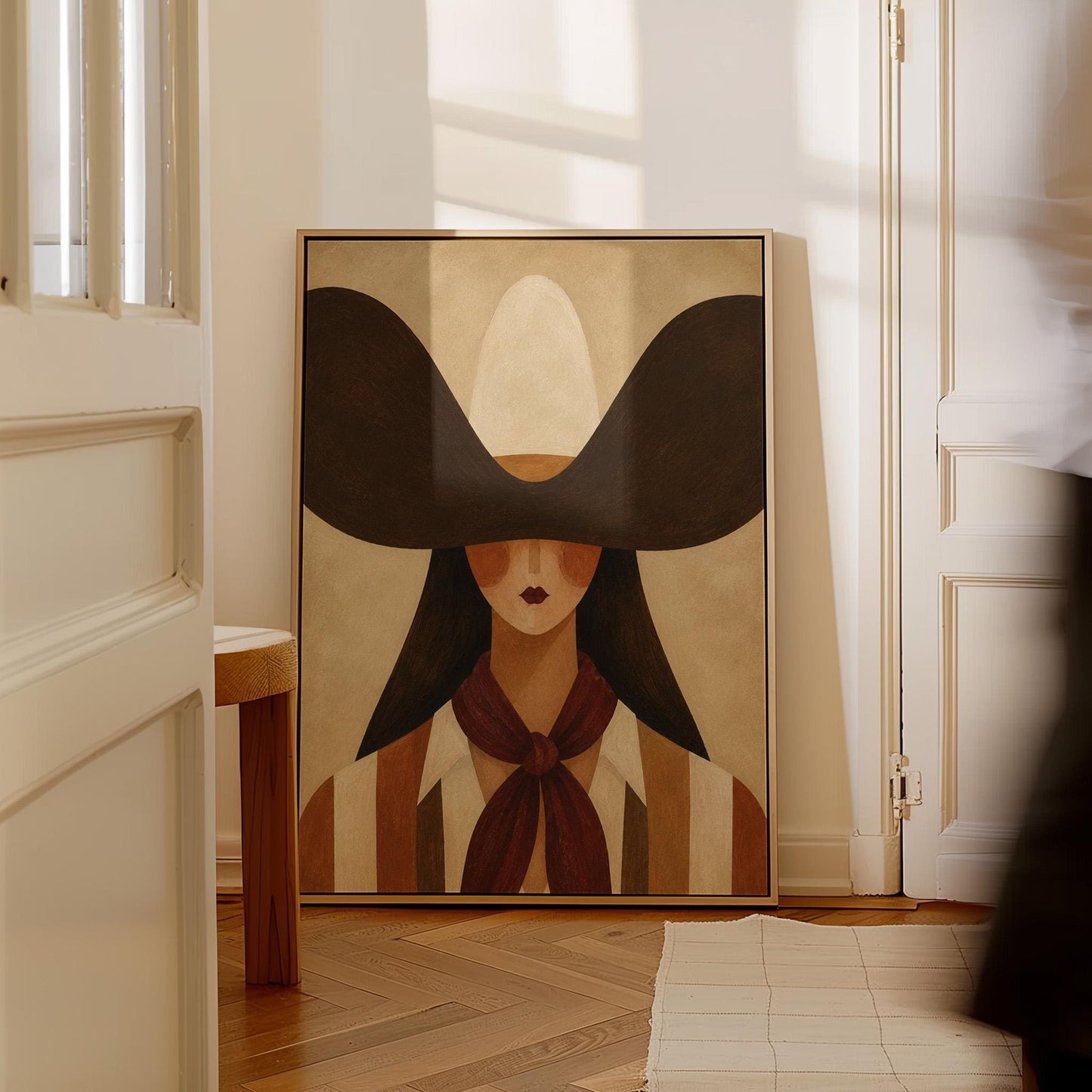 Faceless cowgirl in a wide black hat and mauve neckerchief on tan background, canvas print hanging in a calm, modern living space