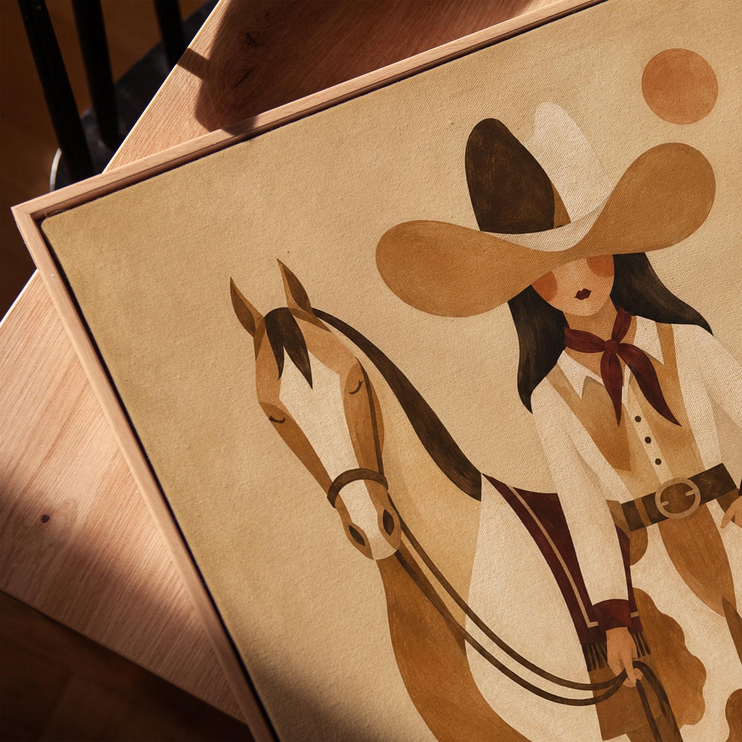 Cowgirl in cow print chaps standing beside a horse in a warm desert scene, canvas print in a warm, minimally styled interior