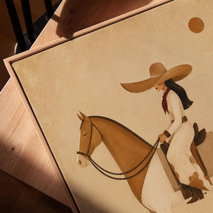 Cowgirl in a broad straw hat riding a cream and chestnut pinto horse, canvas print in a warm, minimally styled interior