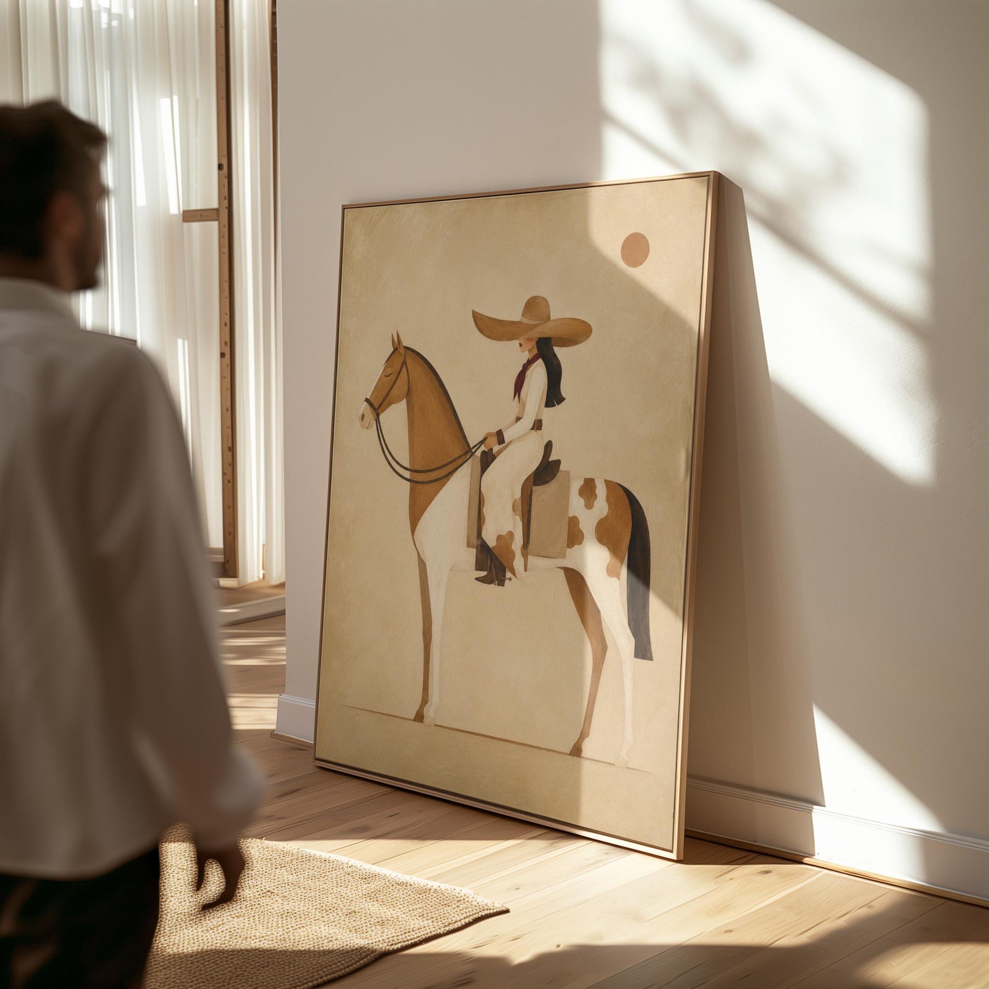 Cowgirl in a broad straw hat riding a cream and chestnut pinto horse, canvas print shown in a sunlit, contemporary room