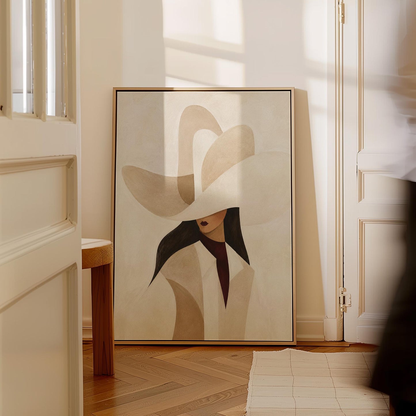 Abstract sculptural cream cowboy hat above a woman in a pale coat, canvas wall art hanging in a calm, modern living space