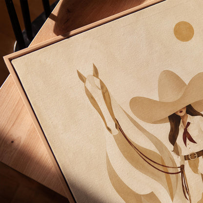 Cowgirl in cream chaps beside a pale horse under a small ochre sun, canvas print in a warm, minimally styled interior