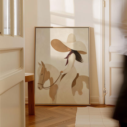 Woman in a long white dress and floppy hat riding a spotted horse, canvas print displayed on a neutral wall in a styled interior