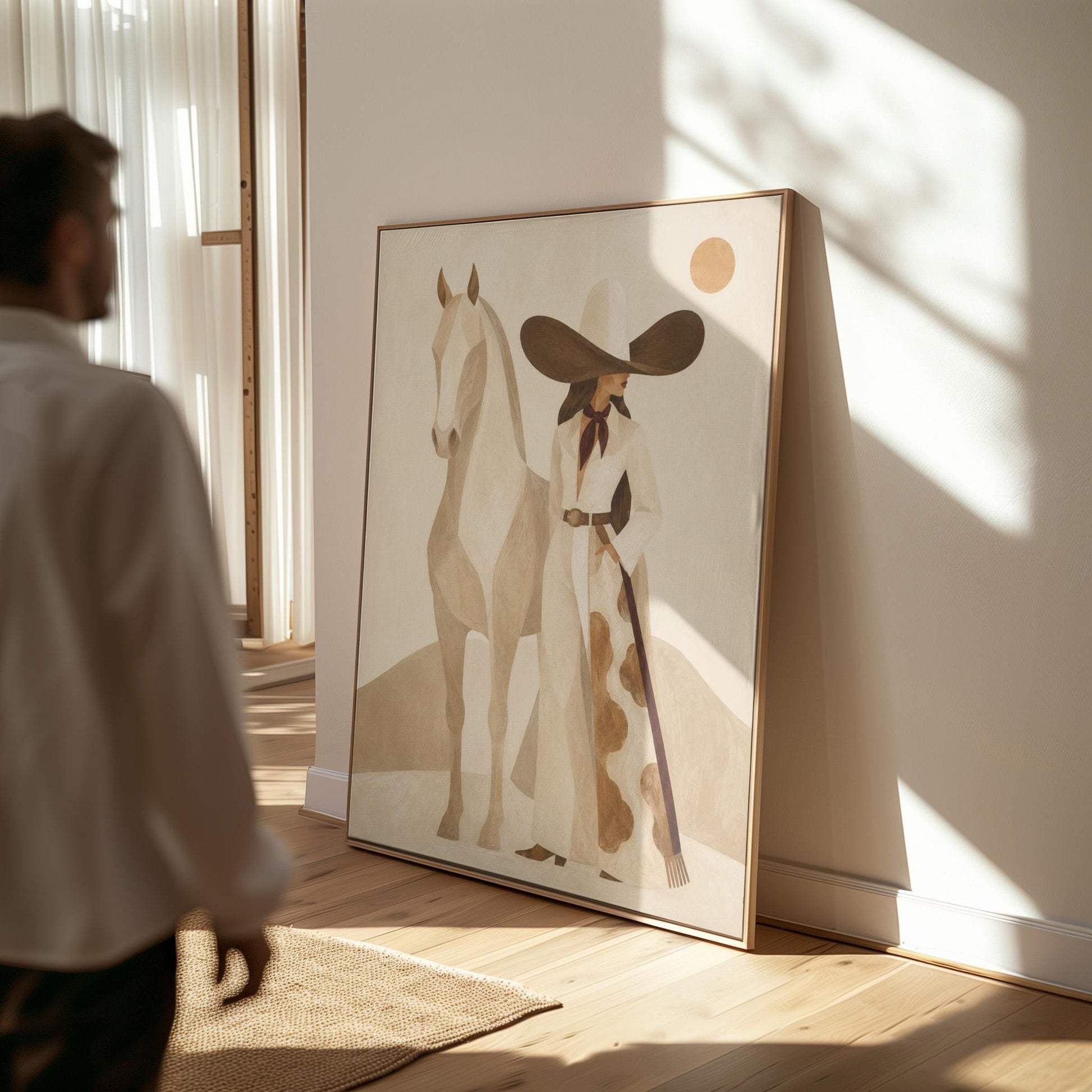 Cowgirl in a dark hat with a pale horse before soft desert hills, canvas print presented in a light, minimal room