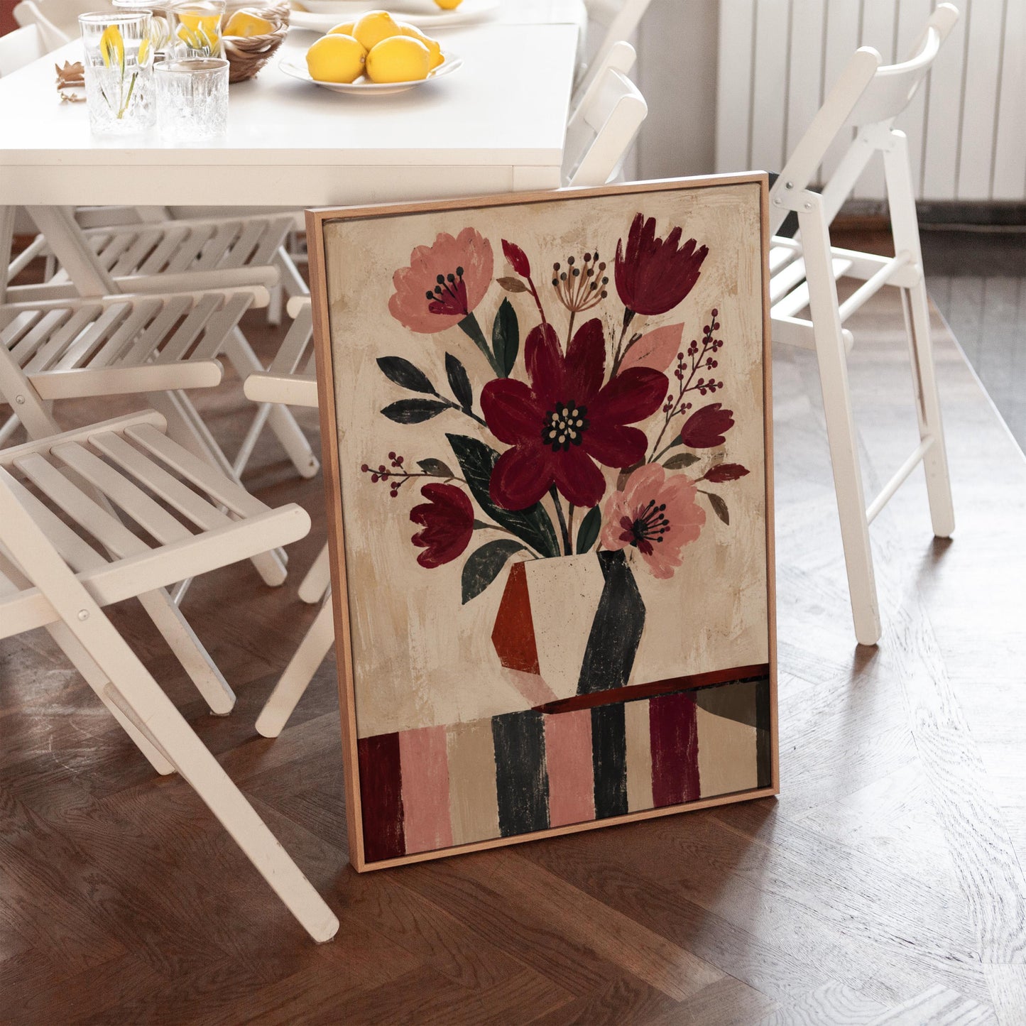 Burgundy and dusty pink flowers in a striped vase on a striped table, canvas wall art on a quiet wall in a considered interior