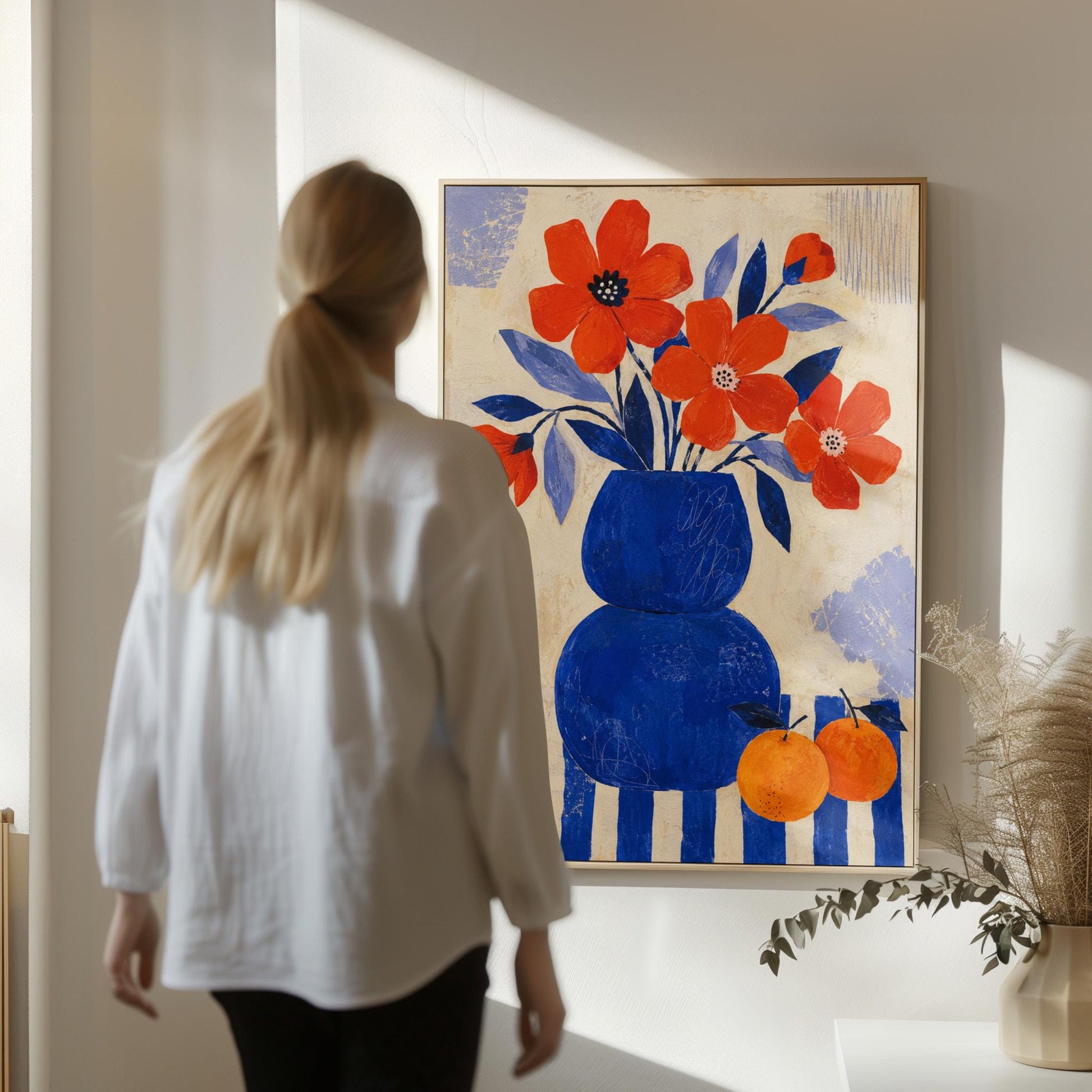 Scarlet poppies in a cobalt vase with oranges on a blue striped cloth, canvas print shown in a sunlit, contemporary room