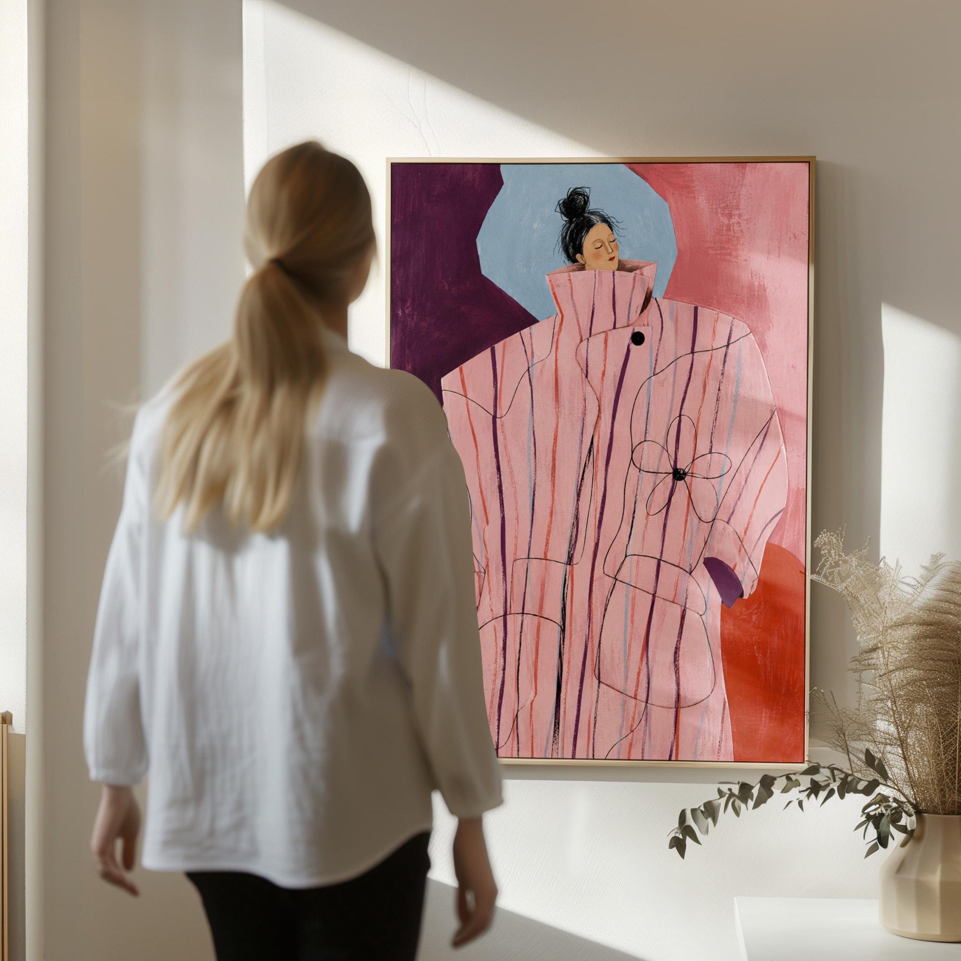Woman in an oversized pink striped coat against plum and coral blocks, canvas print presented in a light, minimal room
