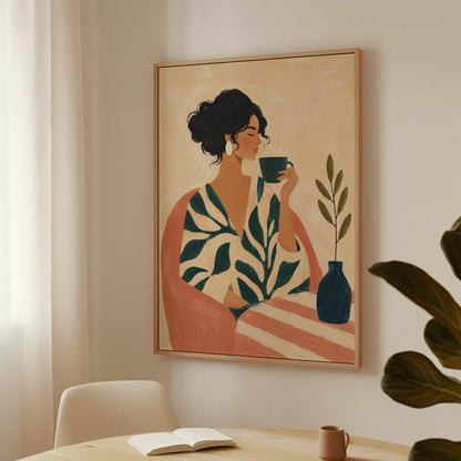 Woman in a leaf print robe drinking from a teal cup beside a vase, canvas wall art styled against a soft white wall