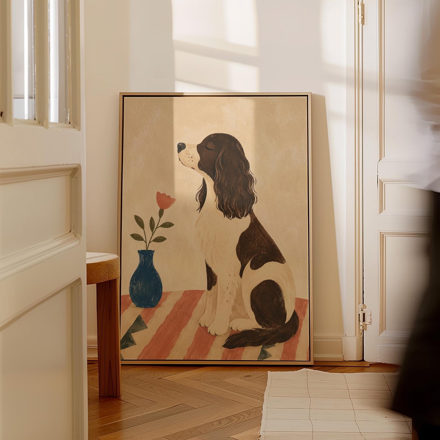 Brown and white spaniel sniffing a coral tulip in a small blue vase, canvas wall art styled against a soft white wall