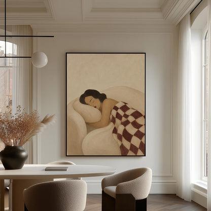Woman sleeping under a burgundy and cream checkerboard blanket, canvas wall art hanging in a calm, modern living space