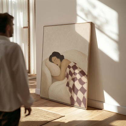 Woman sleeping under a burgundy and cream checkerboard blanket, canvas wall art presented in a light, minimal room
