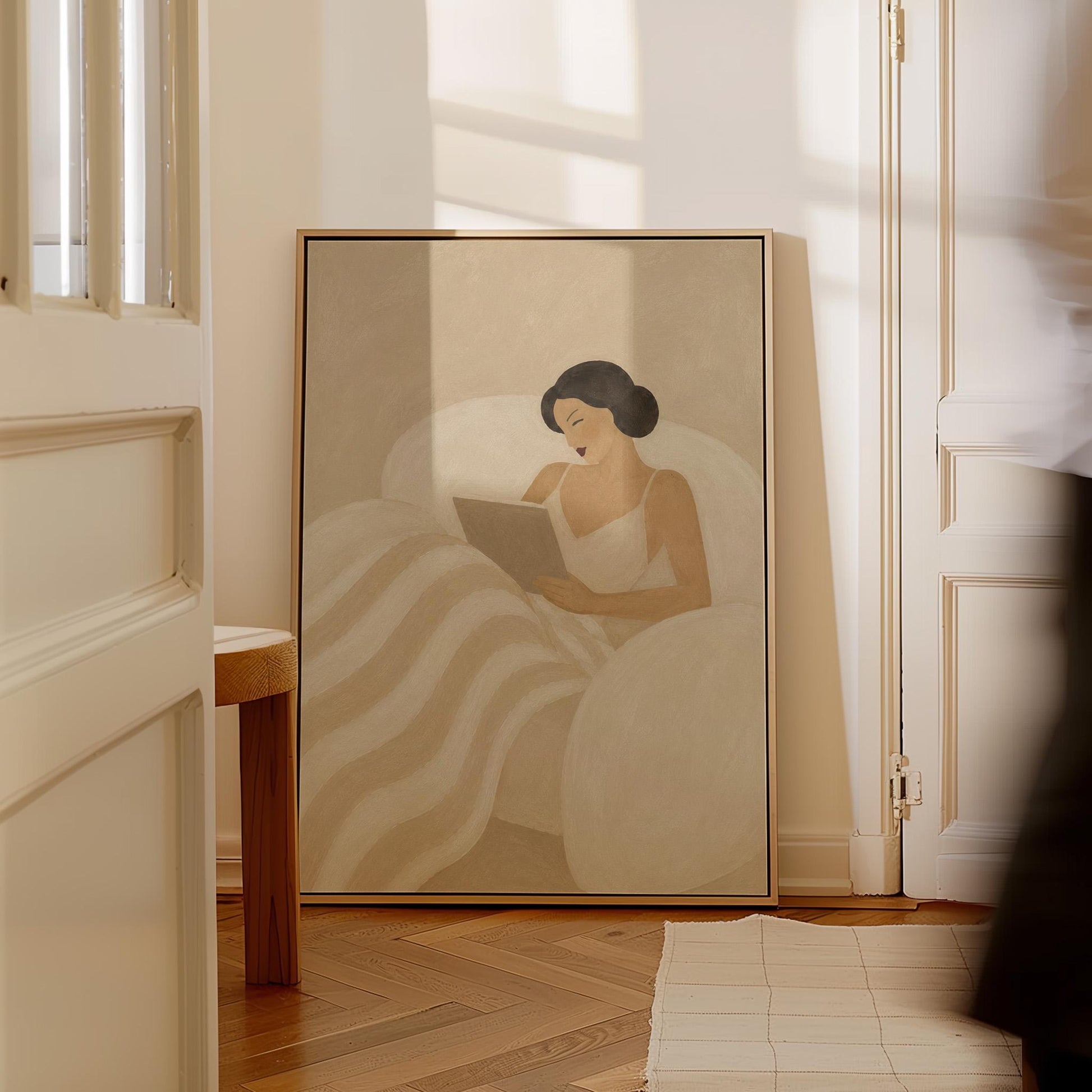 Woman in a white slip sitting up in bed reading in morning light, canvas wall art hanging in a calm, modern living space