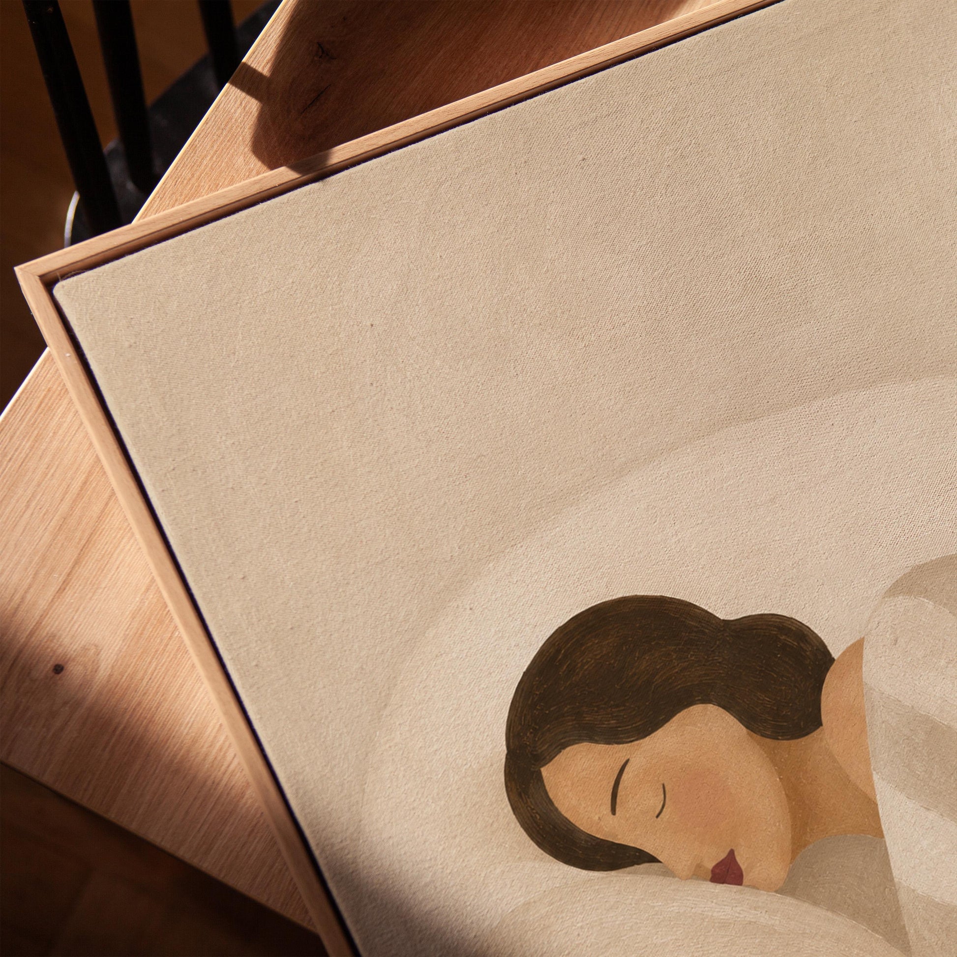 Woman asleep beneath a quilt of rolling cream and sand wave shapes, canvas print in a warm, minimally styled interior