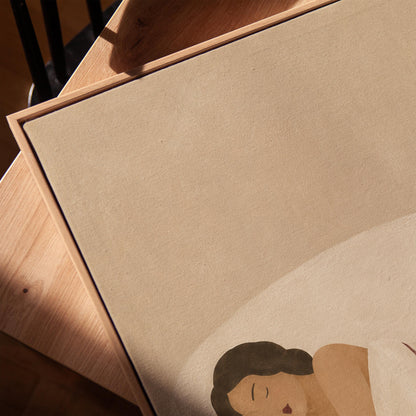 Woman asleep on her side under white linen with thin maroon lines, canvas print in a warm, minimally styled interior