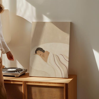 Woman asleep on her side under white linen with thin maroon lines, canvas wall art hanging in a calm, modern living space