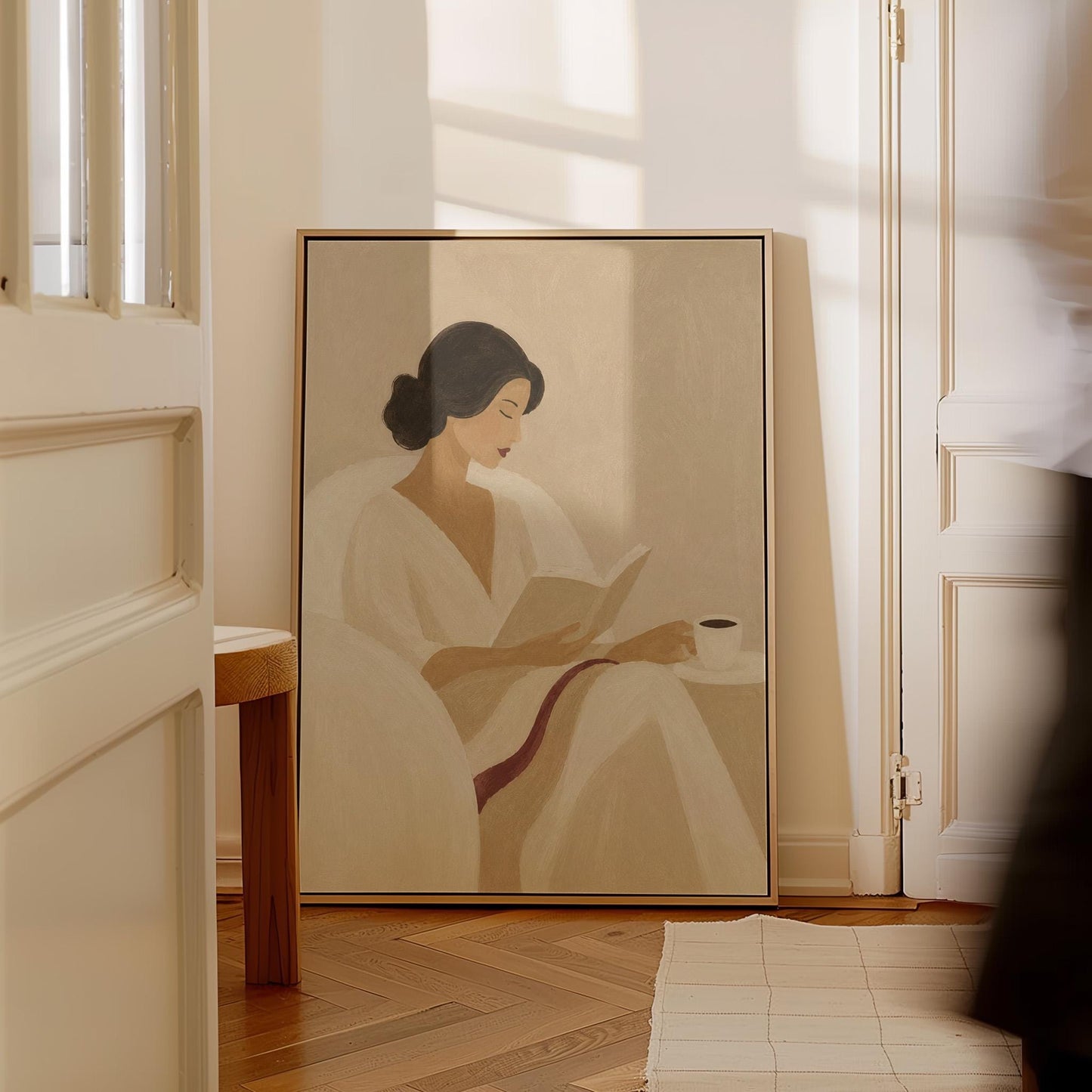 Woman in a white robe reading in an armchair with a black coffee, canvas print shown in a sunlit, contemporary room
