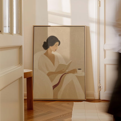 Woman in a white robe reading in an armchair with a black coffee, canvas print shown in a sunlit, contemporary room