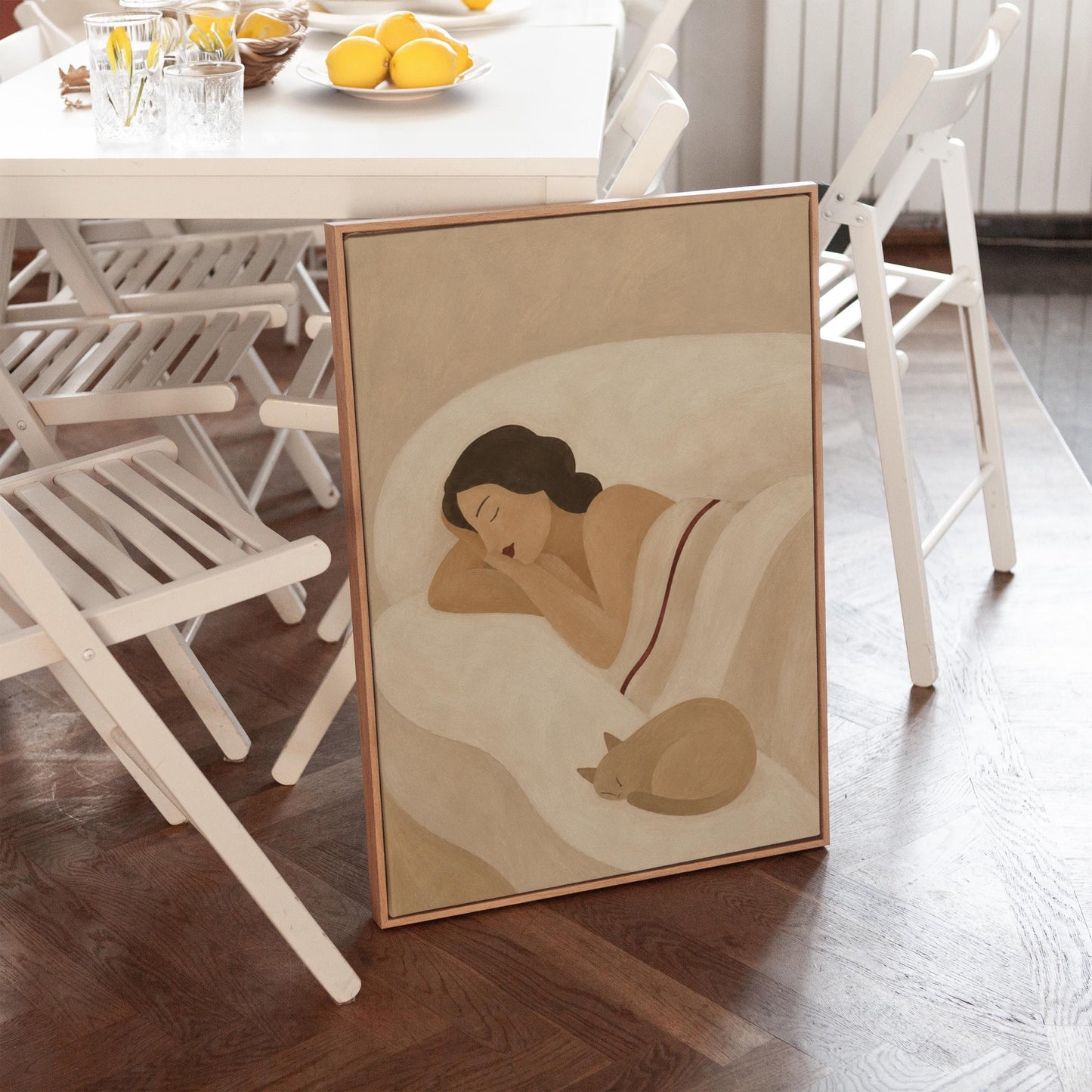 Woman sleeping with a small white cat curled at the foot of the bed, canvas print presented in a light, minimal room