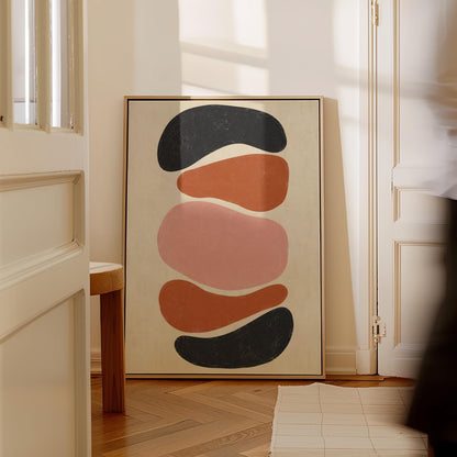 Five stacked pebble shapes in charcoal rust and blush on cream, canvas print seen in a warm interior with natural light