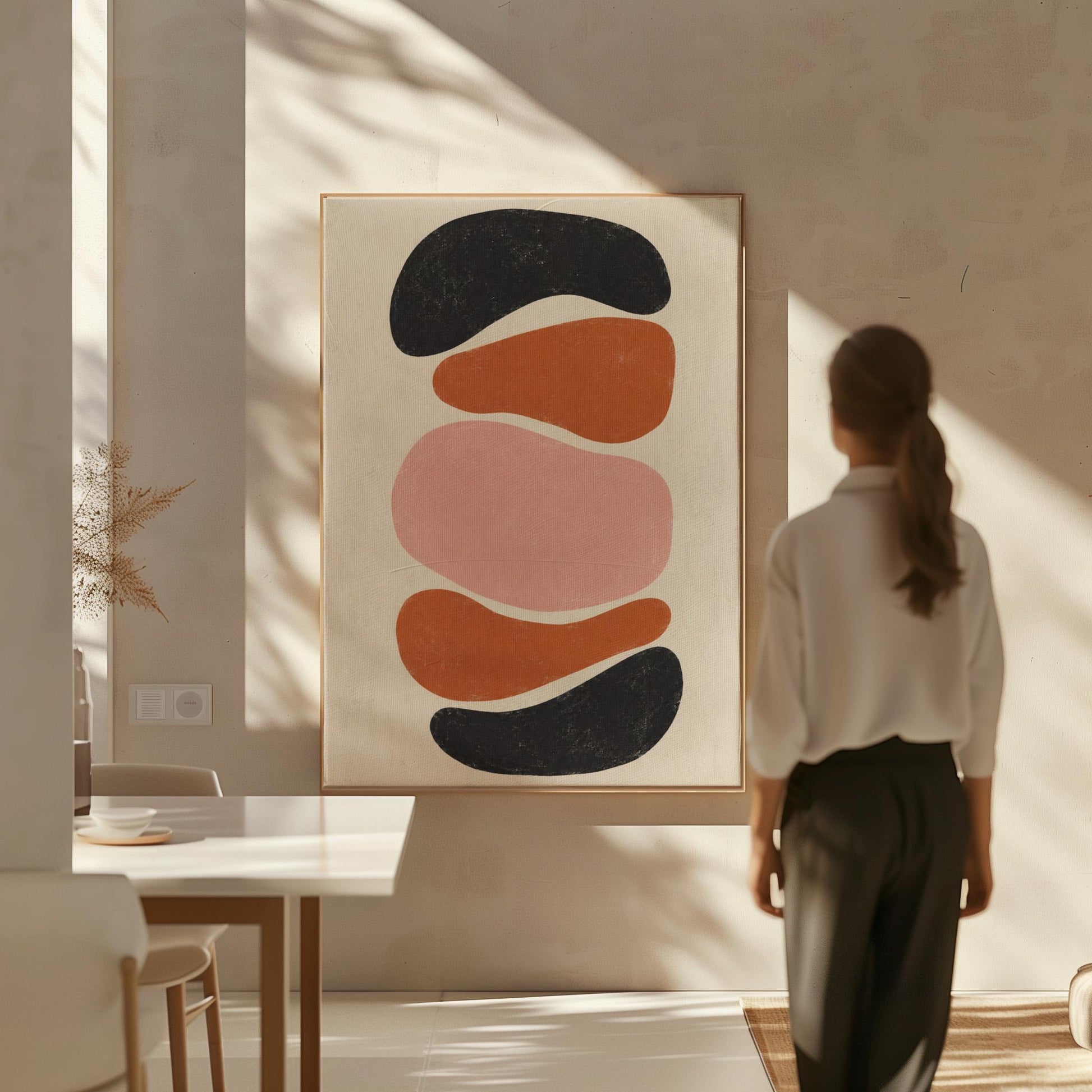 Five stacked pebble shapes in charcoal rust and blush on cream, canvas wall art hanging in a calm, modern living space
