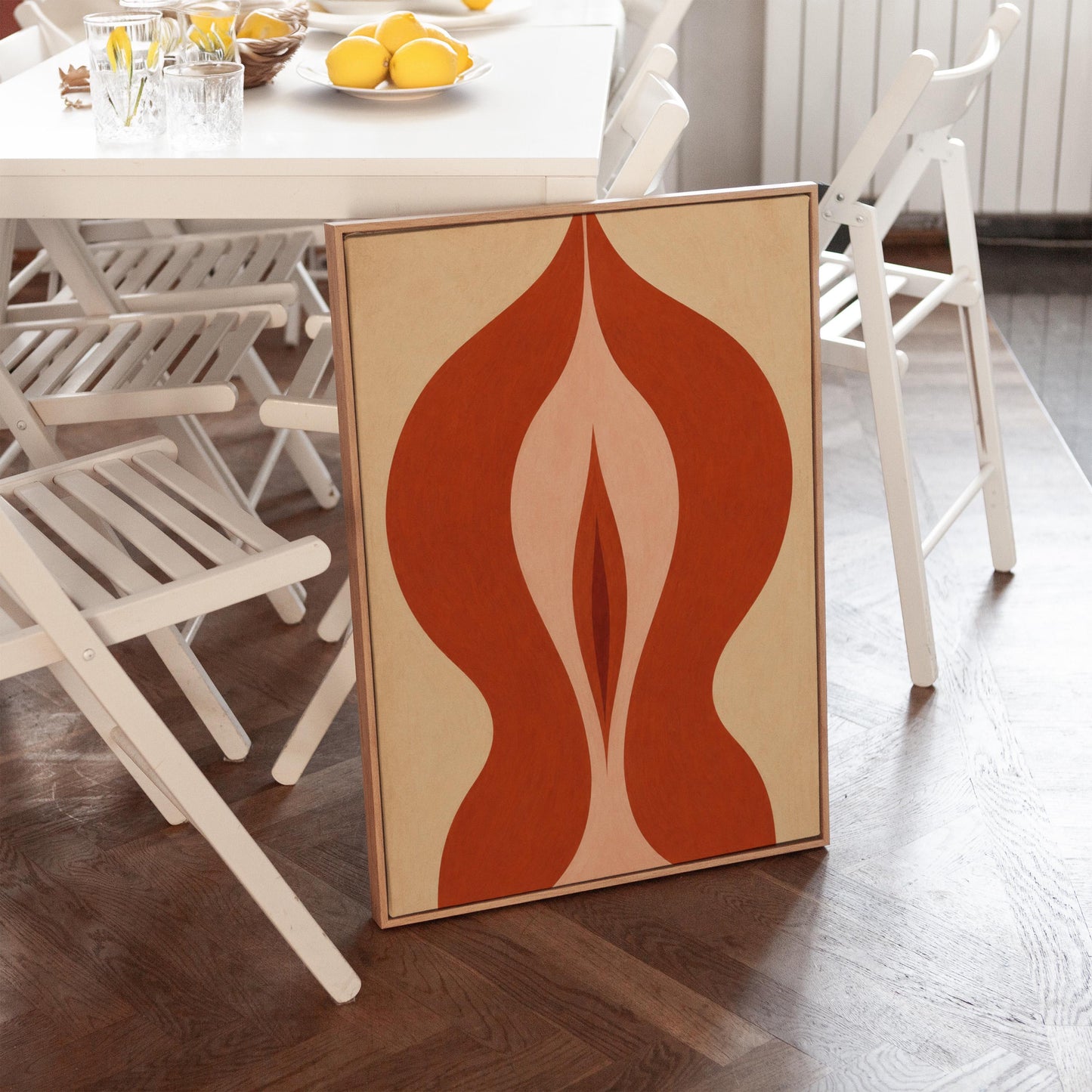 Rust red flame shaped form opening into blush and grey on sand, canvas print shown to scale in a furnished room