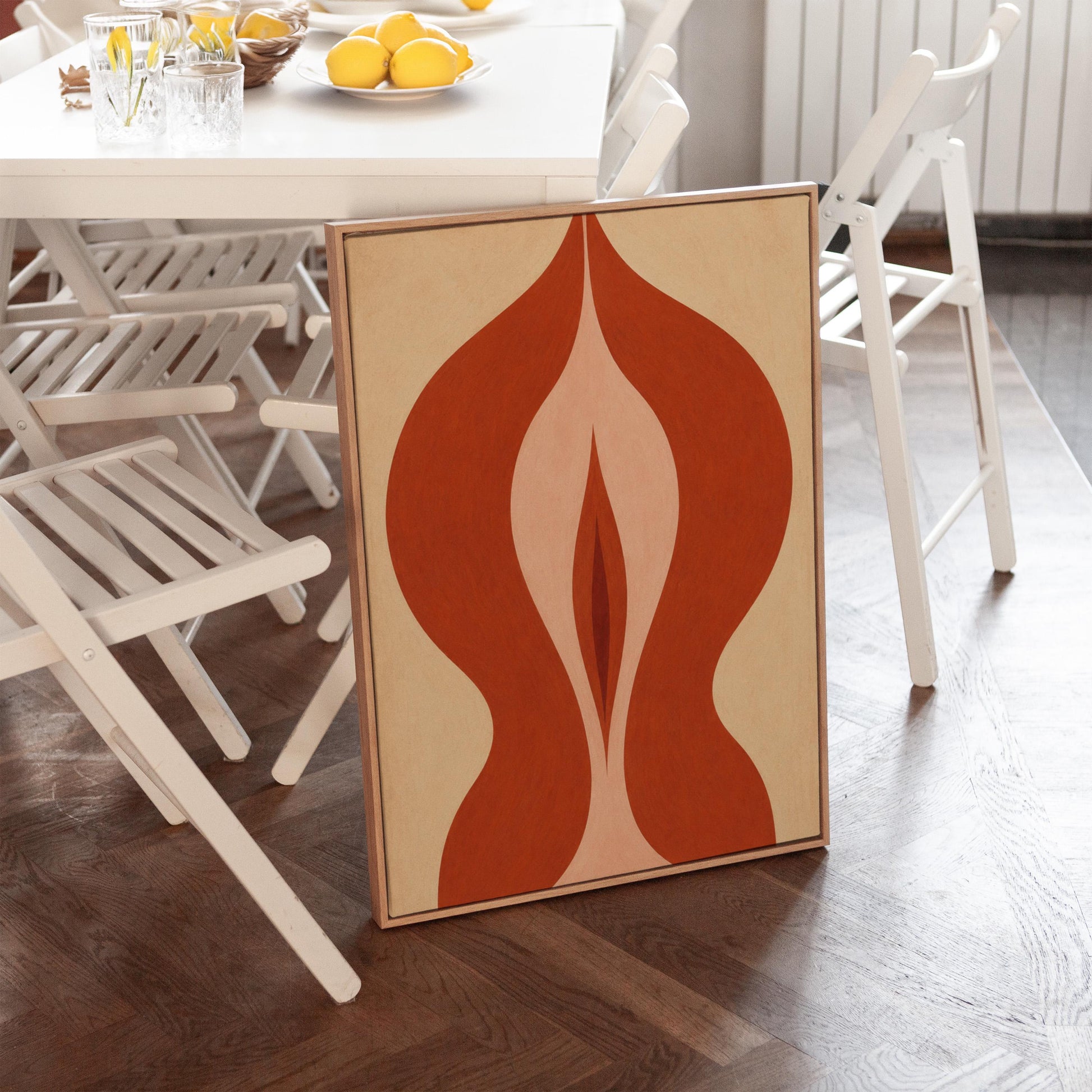 Rust red flame shaped form opening into blush and grey on sand, canvas print shown to scale in a furnished room
