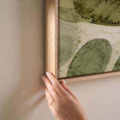 Overlapping olive green stone shapes, canvas print shown at full size in a light-filled bedroom