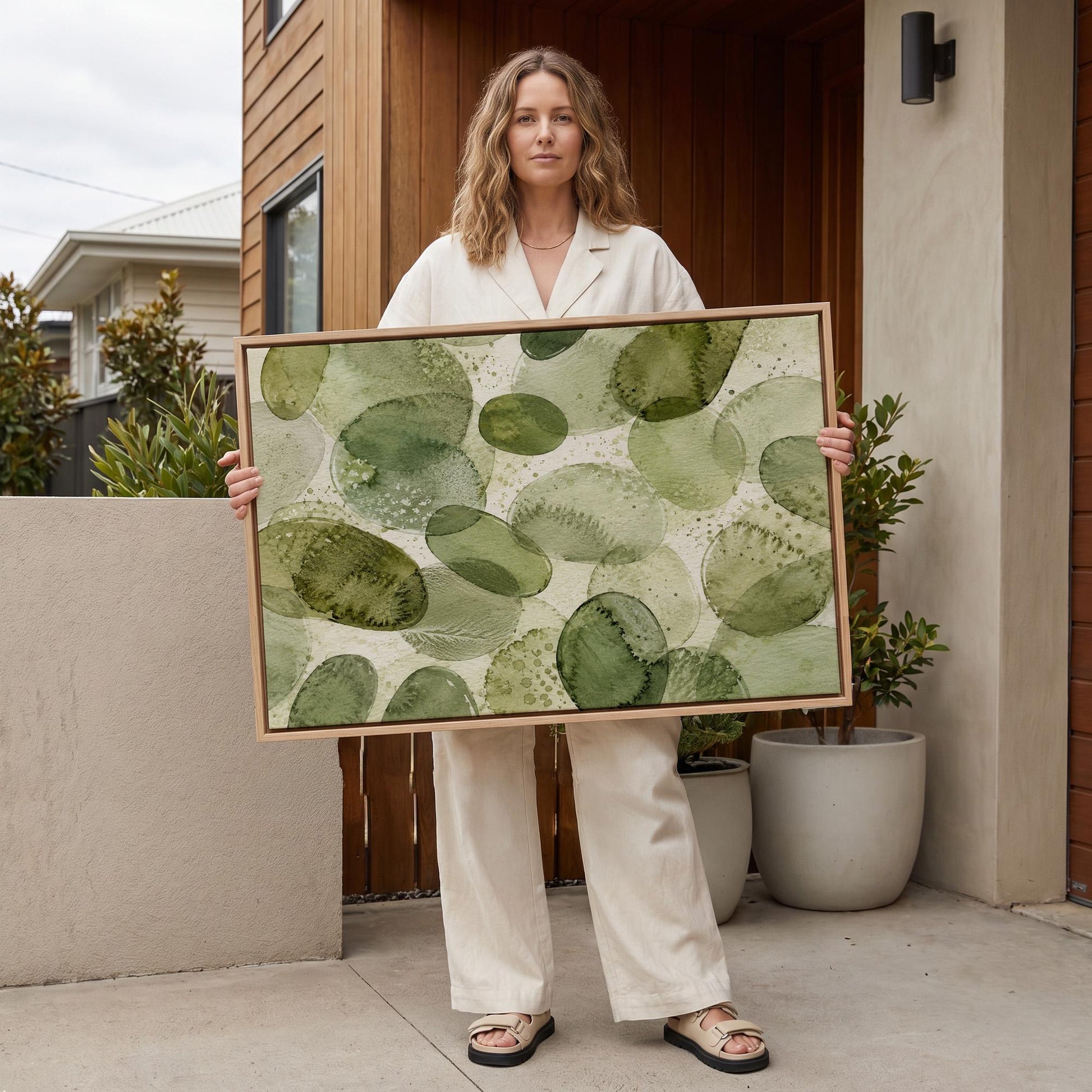 Overlapping olive green stone shapes, canvas print hanging in a calm, modern living space