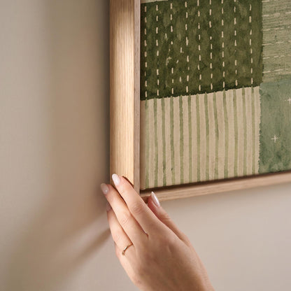 Quilted patchwork of olive green blocks, canvas print shown at full size in a light-filled bedroom