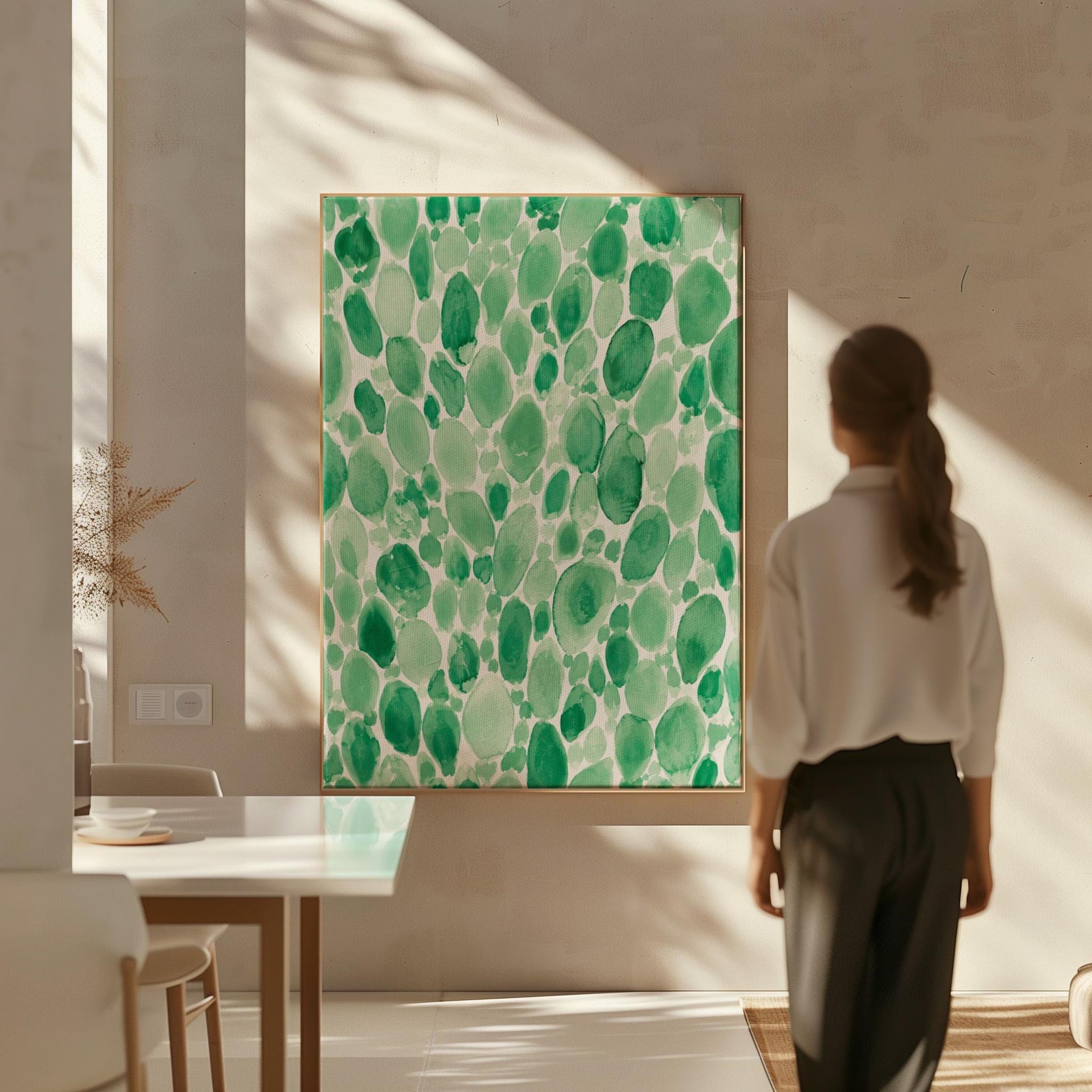 Dense watercolor pebble shapes in mint to emerald green, canvas print displayed on a neutral wall in a styled interior