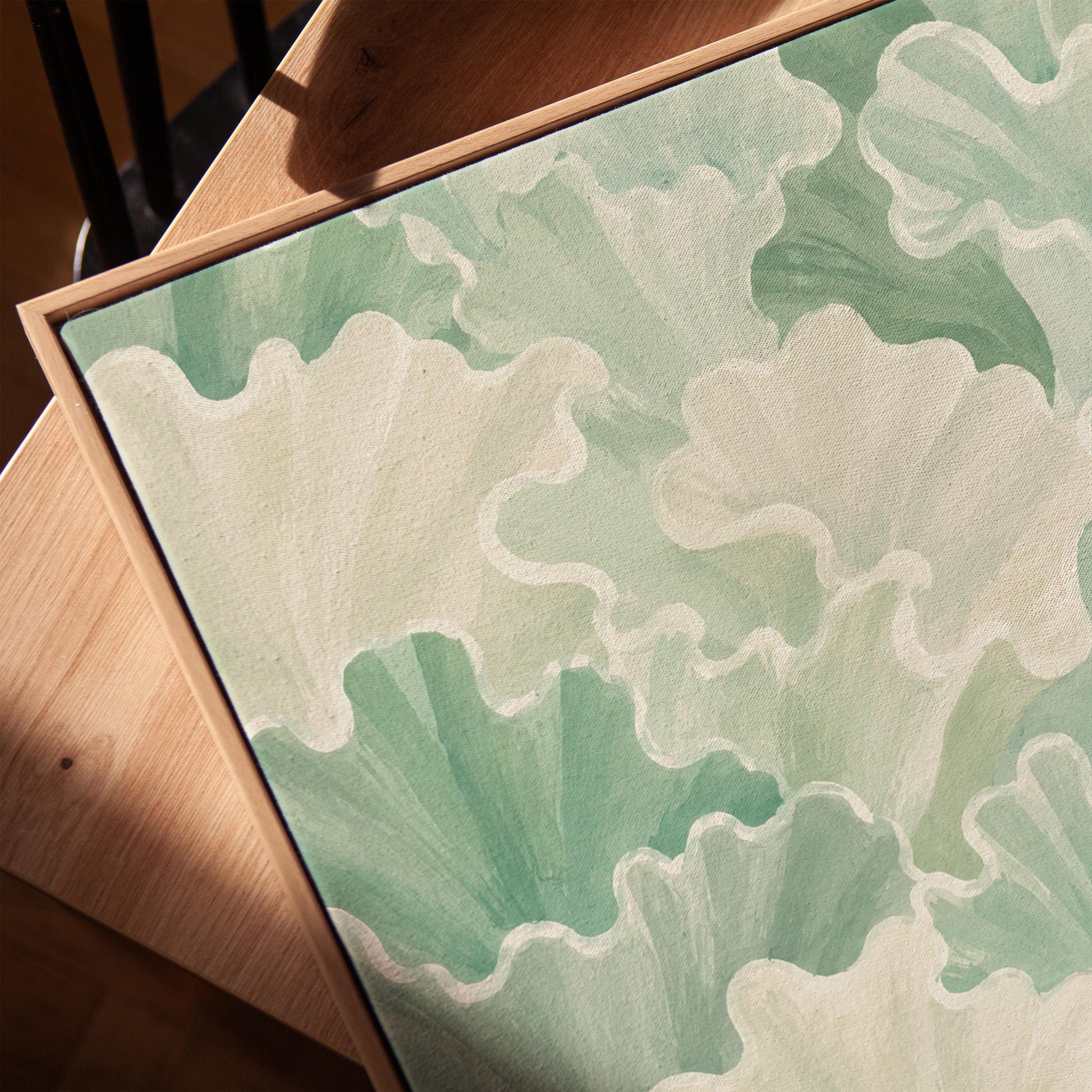 Fan shaped leafy forms in soft sage green watercolor, canvas print in a warm, minimally styled interior