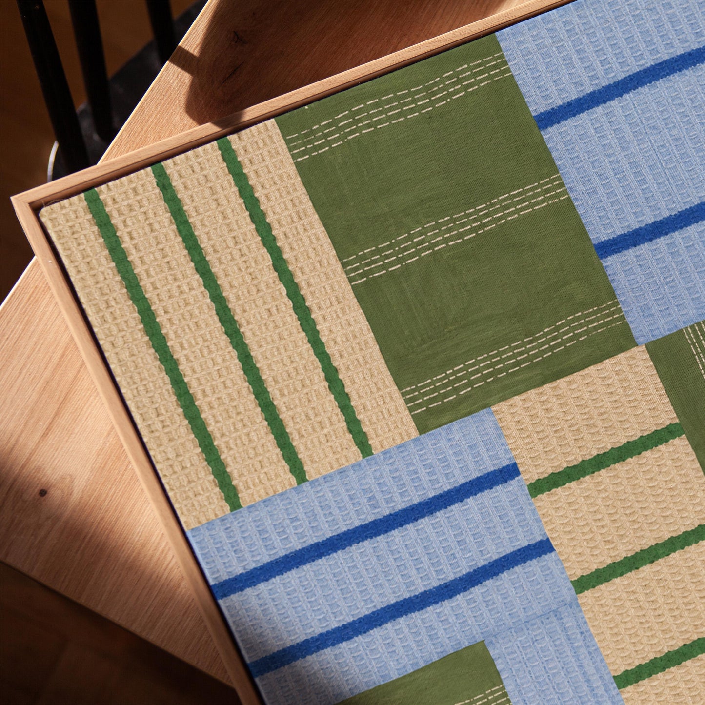 Patchwork of sage green fields with periwinkle blue bands, canvas print in a warm, minimally styled interior