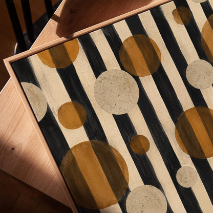 Amber and cream circles scattered over black vertical stripes, canvas print in a warm, minimally styled interior