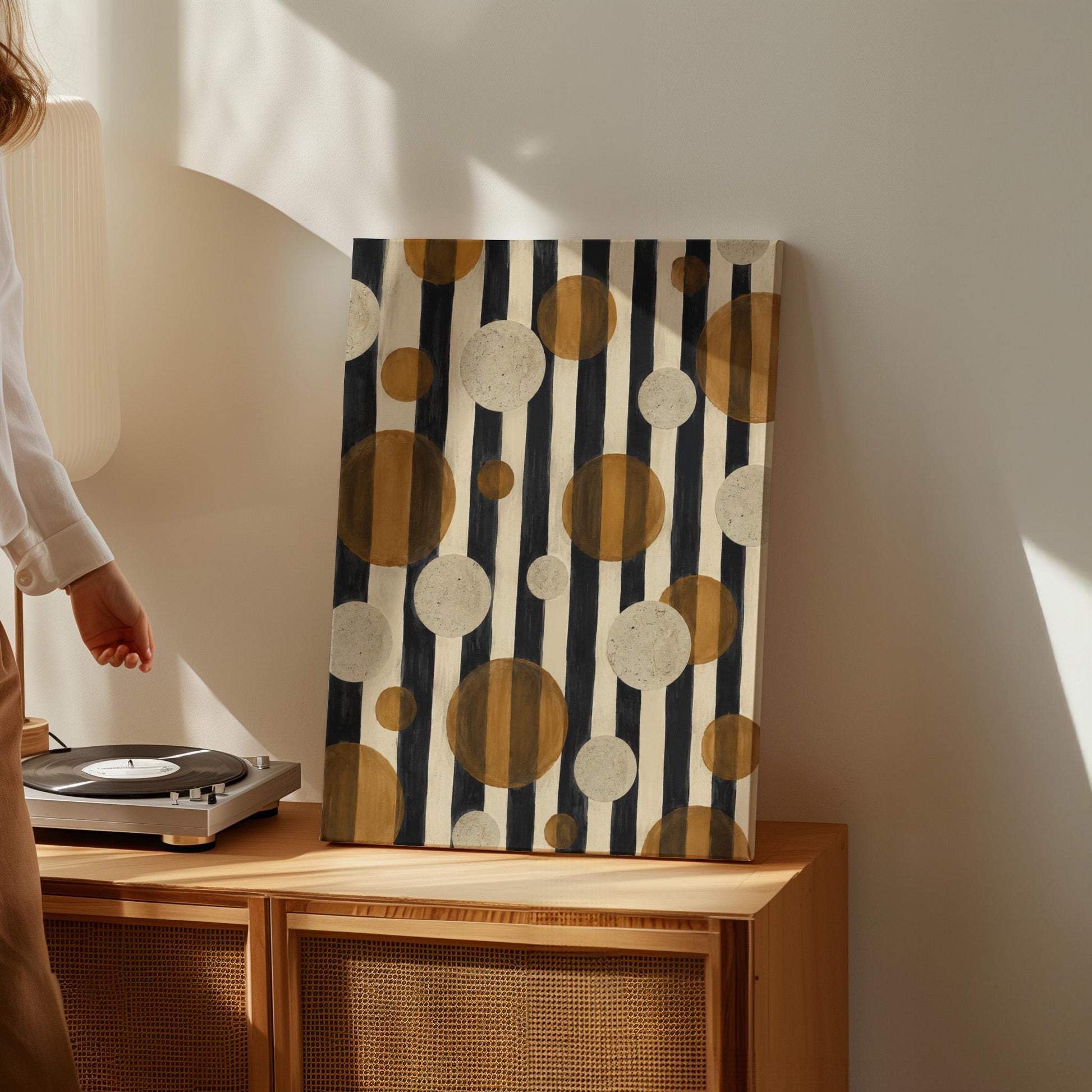 Amber and cream circles scattered over black vertical stripes, canvas print presented in a light, minimal room