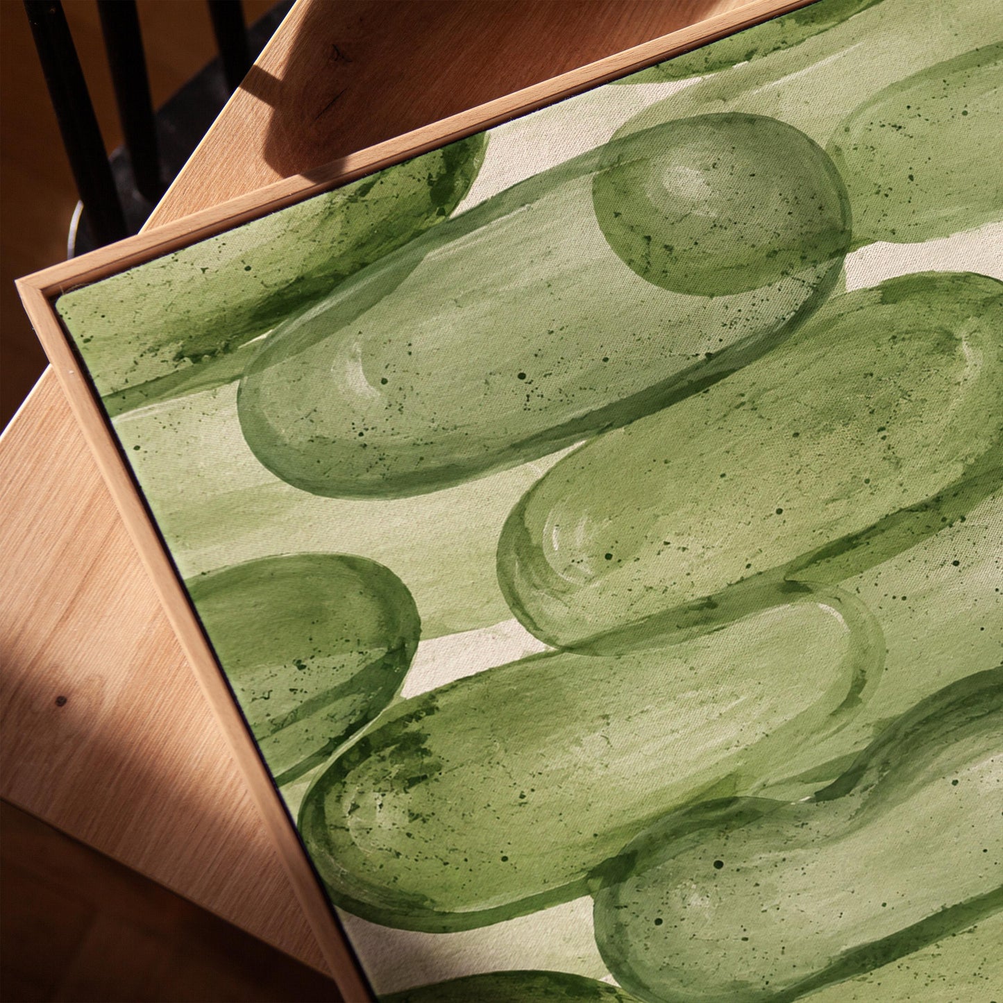 Stacked smooth green stones painted in watercolor, canvas print in a warm, minimally styled interior