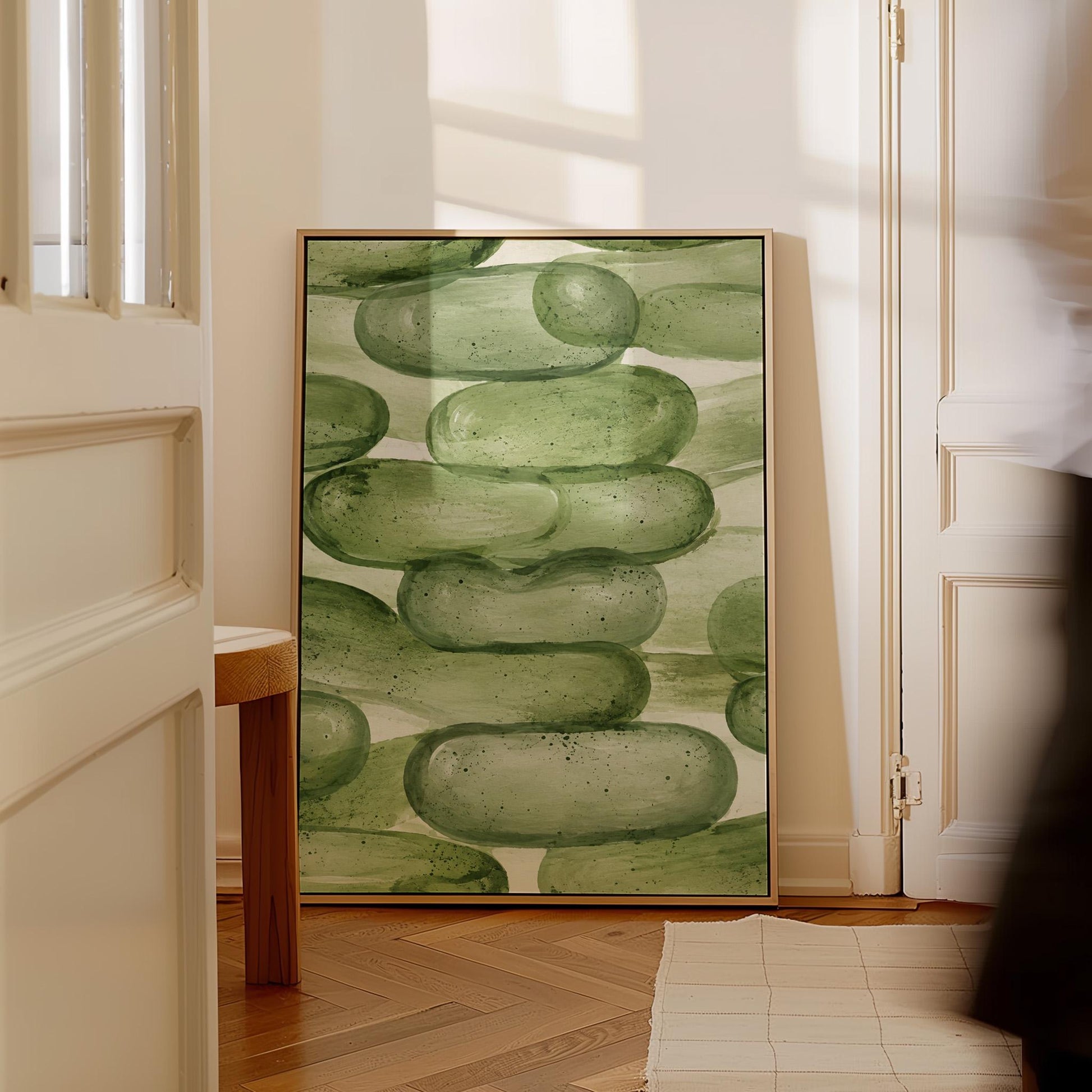 Stacked smooth green stones painted in watercolor, canvas print hanging in a calm, modern living space