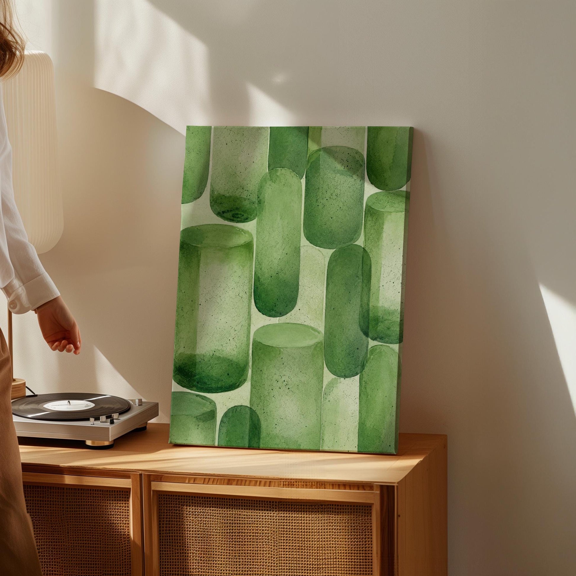 Rounded capsule shapes in layered watercolor greens, canvas wall art hanging in a calm, modern living space