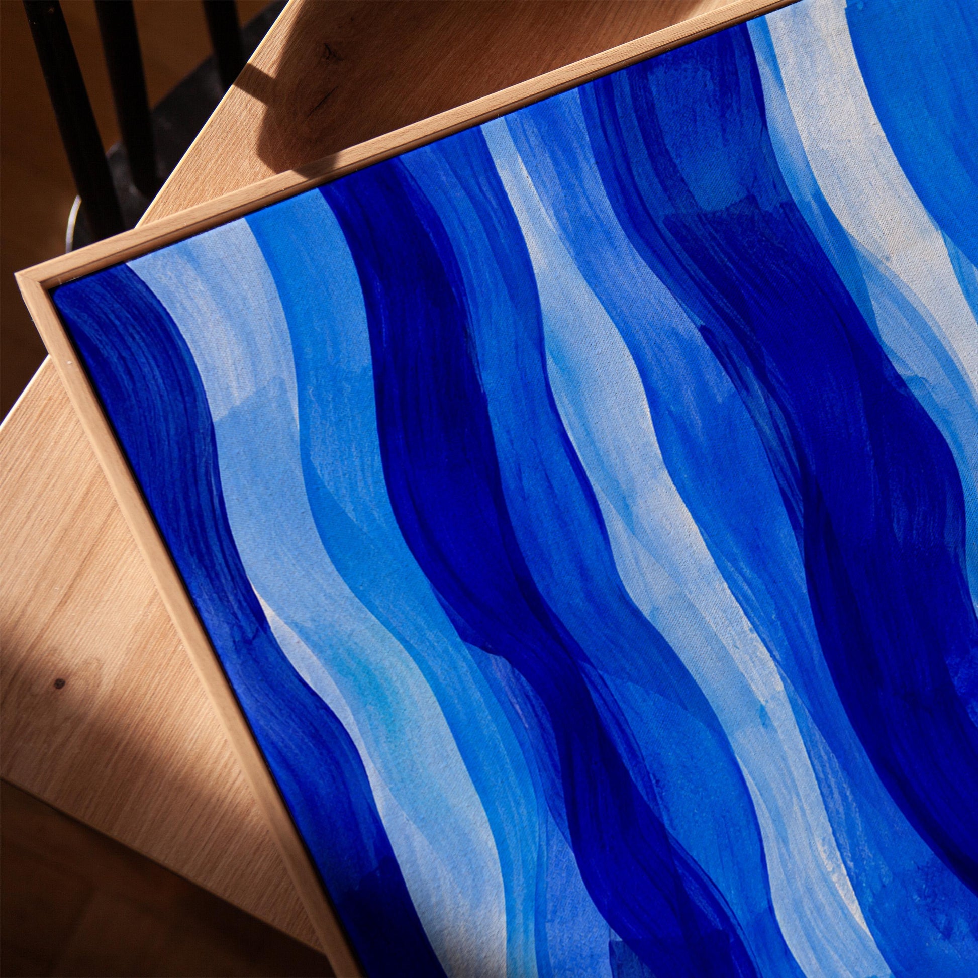 Vertical flowing ribbons in cobalt and light blue, canvas print in a warm, minimally styled interior