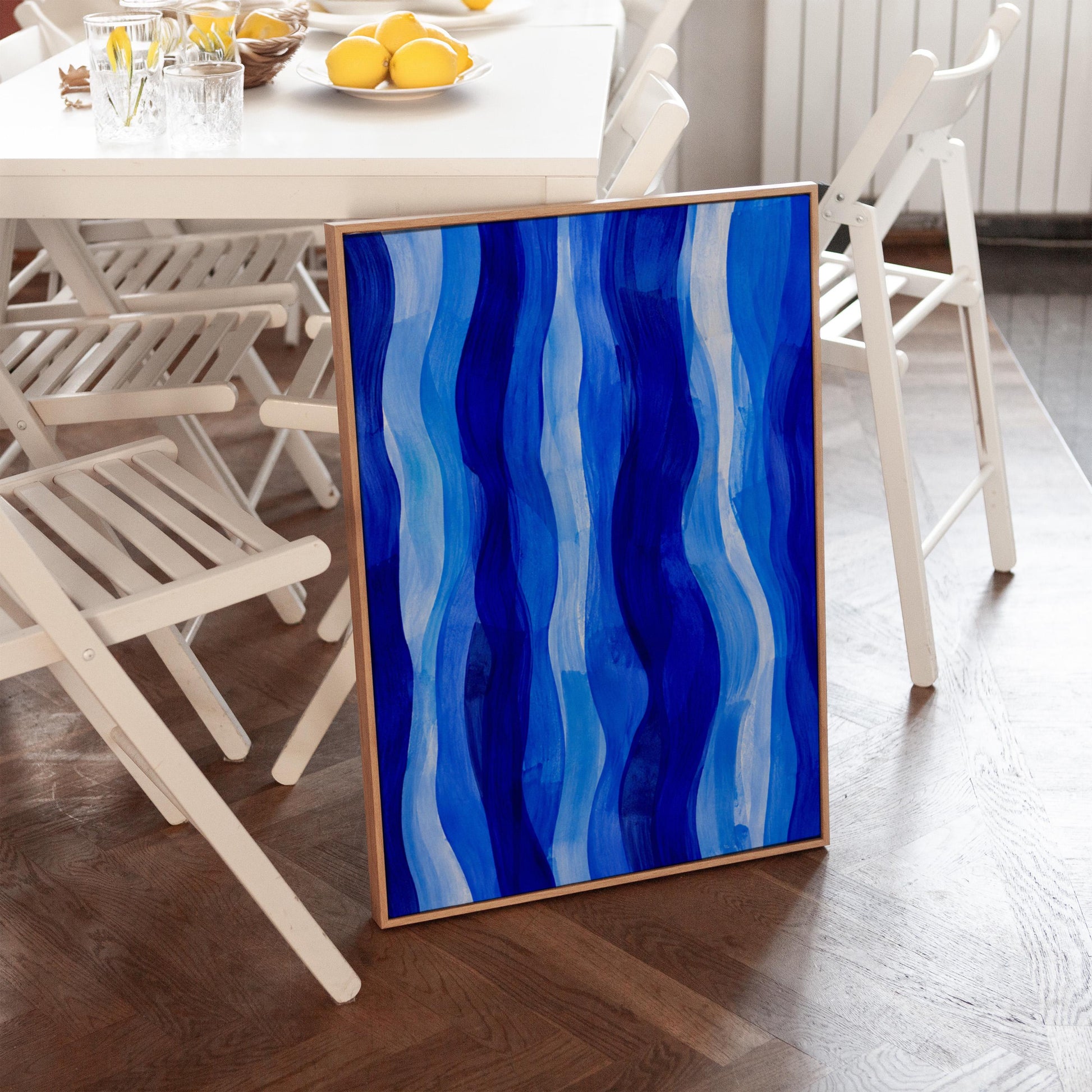 Vertical flowing ribbons in cobalt and light blue, canvas wall art presented in a light, minimal room