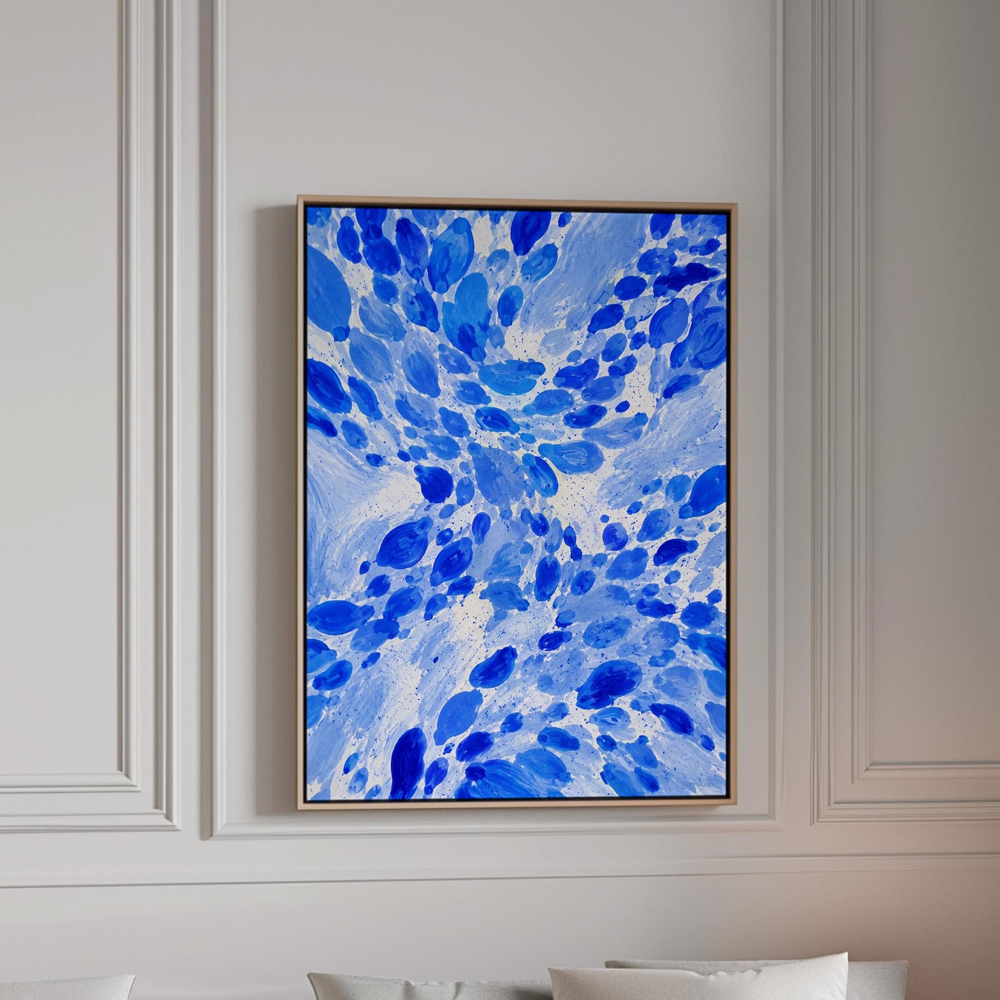 Burst of cobalt blue droplets scattering across pale background, canvas print in a bright room with natural daylight