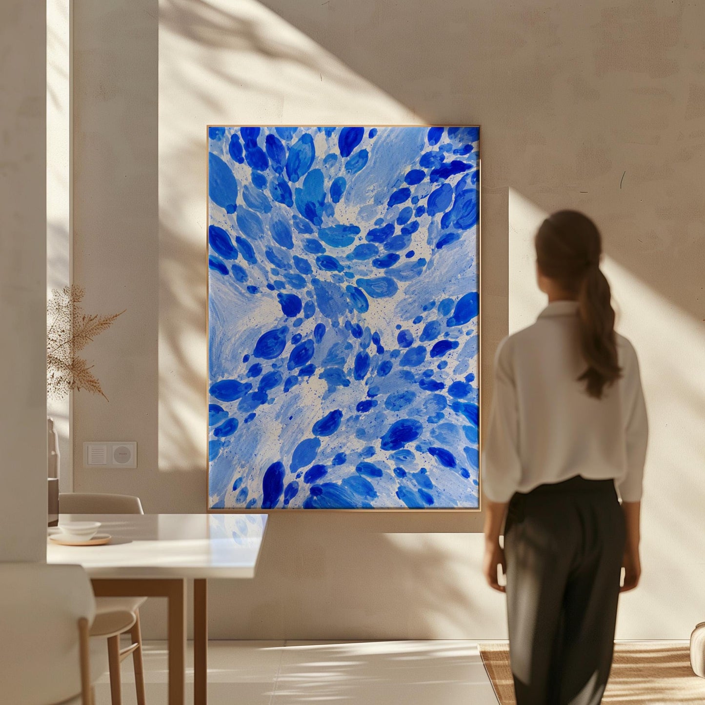 Burst of cobalt blue droplets scattering across pale background, canvas print presented in a light, minimal room