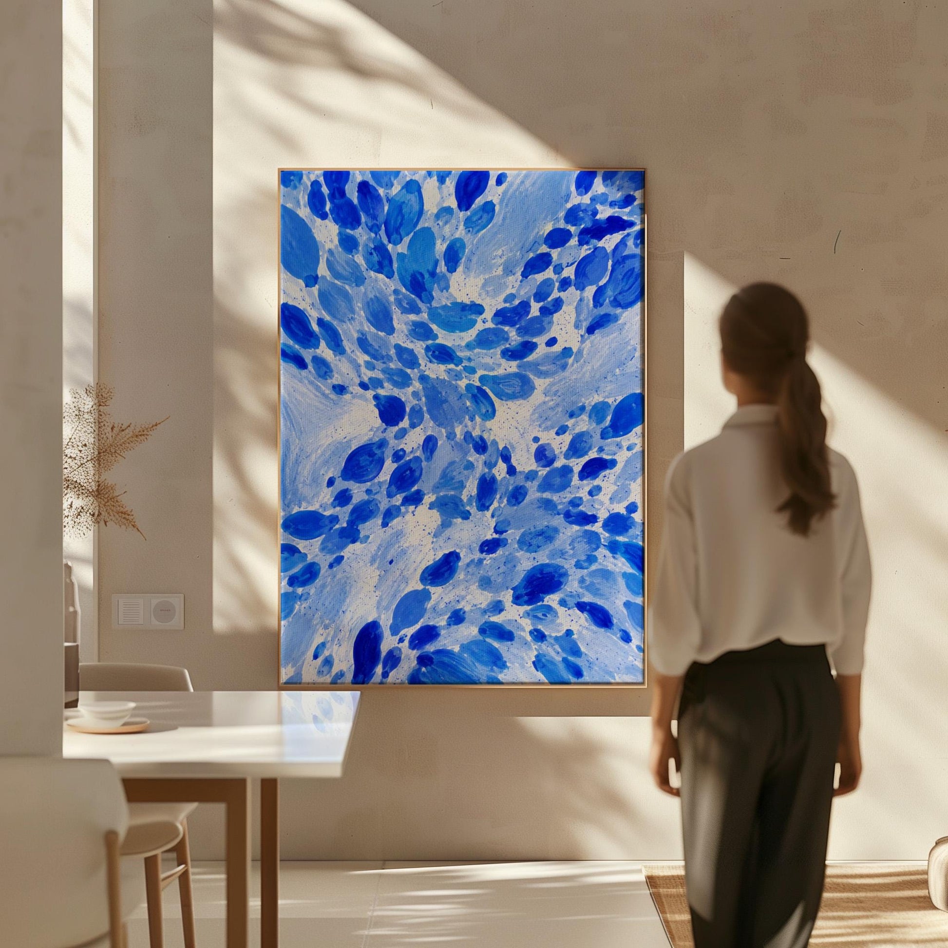 Burst of cobalt blue droplets scattering across pale background, canvas print presented in a light, minimal room